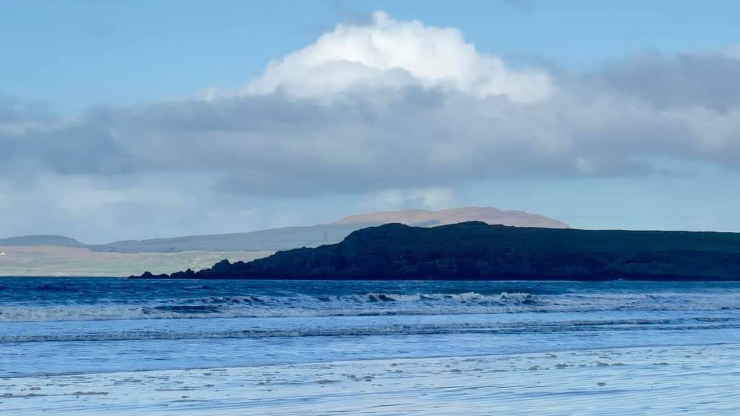 Long waves crossing a Scottish bay beneath a broad sky