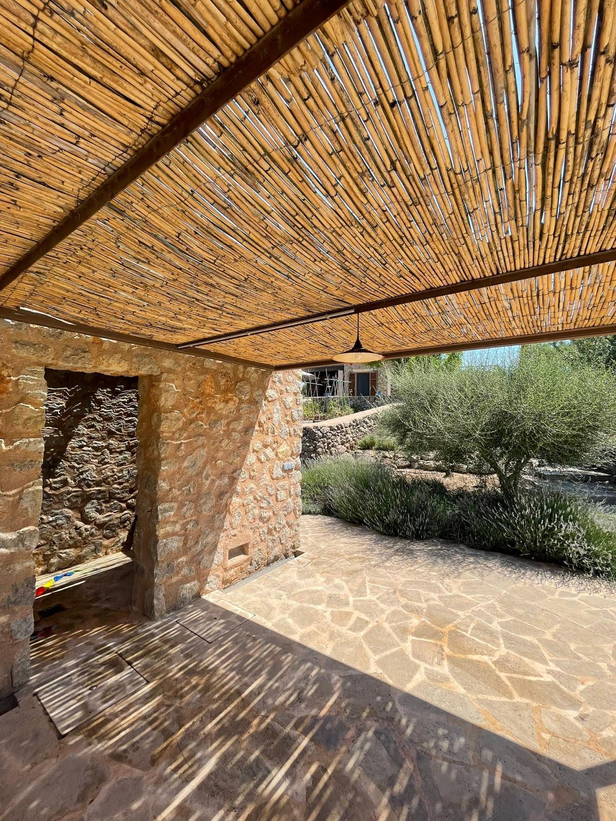 A stone wall beneath a woven reed canopy